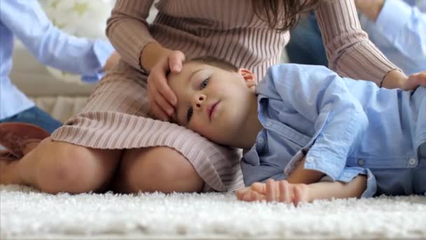 Pequeño hijo está acostado en las rodillas de las madres, en el suelo mientras mamá lo acaricia — Vídeo de stock