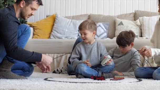 Familie bouwt samen thuis een spoorweg op kerstavond — Stockvideo