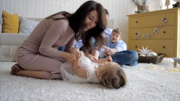 Gelukkig mam kietelt haar kleine lachende dochter op de vloer, close-up — Stockvideo