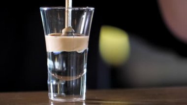 Barman is making alcohol cocktail with three layers