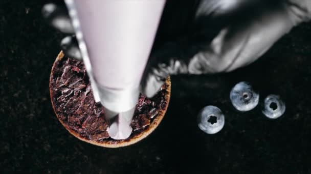 Pastelero decora galleta con crema púrpura de la bolsa de pastelería, primer plano . — Vídeos de Stock