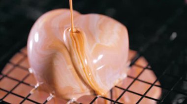 Close-up of a pouring glazing over heart shape dessert in slow motion.