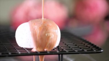 Close-up of a pouring glazing over heart shape dessert in slow motion.