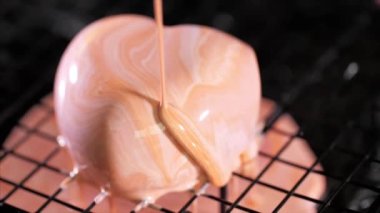 Close-up of a pouring glazing over heart shape dessert in slow motion.