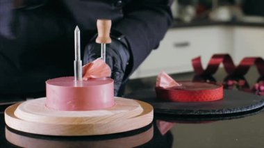 Confectioner is making a petals from pink chocolate on round cutter