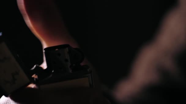 Close-up of a male hand lights a fuel lighter in the dark — Stock Video