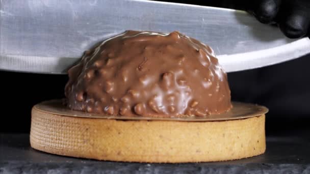 Крупным планом шеф-повара является разрезание десерта молочным шоколадом и орехами — стоковое видео