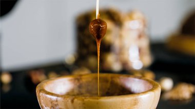 Pastry chef is dips a hazelnut in caramel for making topping for a cake