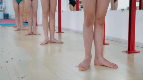 Тонкие ноги девочек делают упражнения во время урока хореографии, крупным планом — стоковое видео