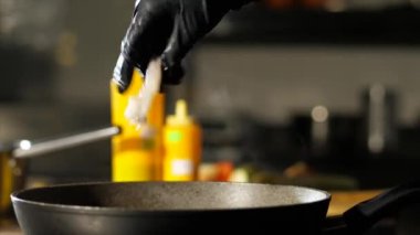 Aşçı ticari mutfakta tavada yemek pişiriyor.