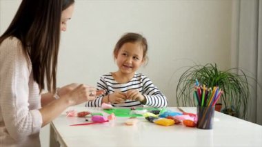 Anne ve kızı birlikte balçıkla oynuyorlar.