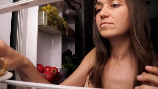 Femme ouvre un réfrigérateur, prend un dessert sucré et grignote la nuit — Video