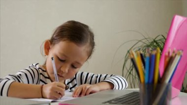 Küçük kız evde internetten çalışıyor.