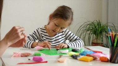 Anne ve kızı birlikte balçıkla oynuyorlar.