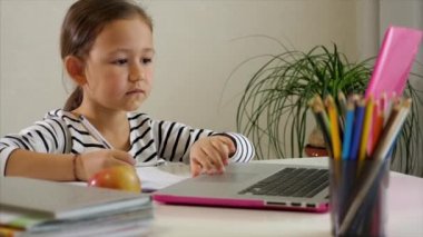 Küçük kız evde internetten çalışıyor.