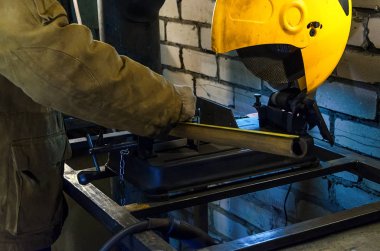 İşçi, makine üzerinde kesmek için metal boru ellerini tutar. Beyaz tuğla arka planı