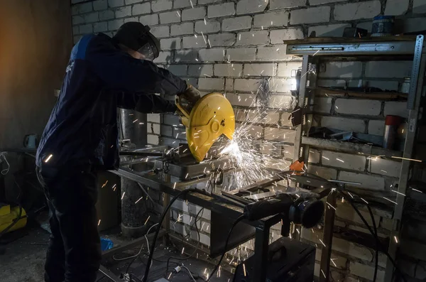 Il lavoratore tiene per mano il tubo metallico per tagliarlo sulla macchina. Sullo sfondo di mattoni bianchi — Foto Stock