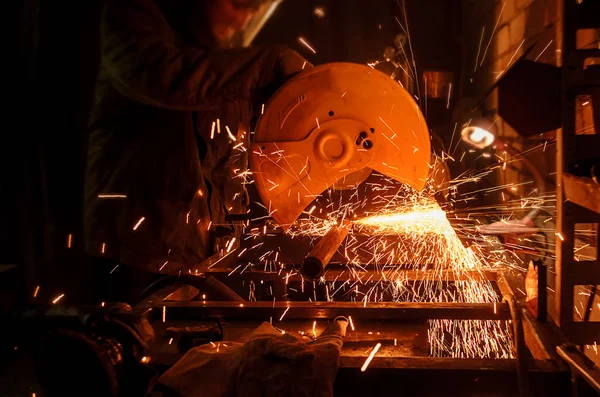 Processo di taglio di tubi metallici sulla macchina. Le scintille volano in direzioni diverse al buio — Foto Stock