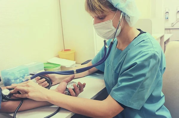 Acil klinikte Doktor hastaya bir phonendoscope kullanarak tablo üzerinde basınç ölçer