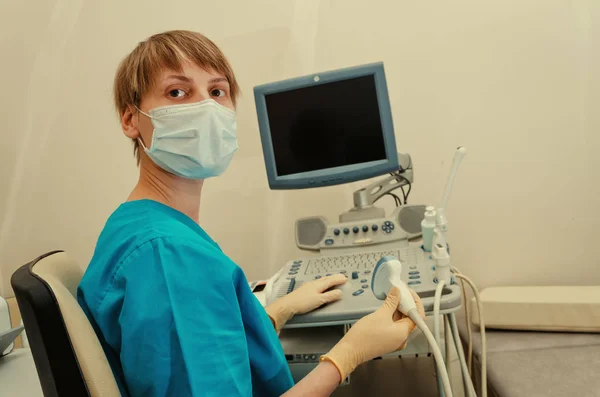 Bir sabahlık doktor ultrason cihazları yakınındaki üzerinde bir istemci bekliyor