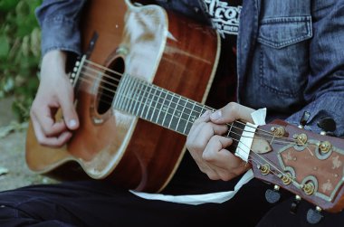 Genç adam gitar çalıyor. Görünür el ve gitar