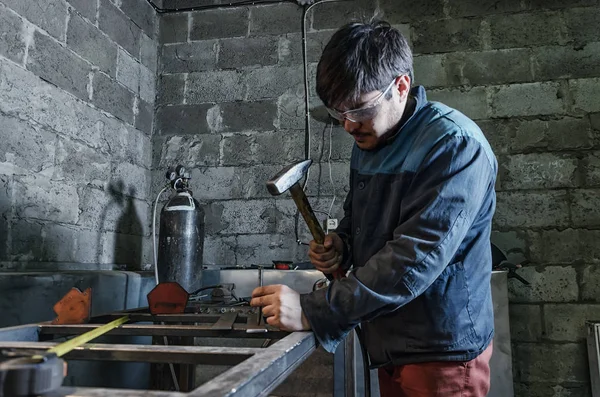 Porträt eines Mannes mittleren Alters mit grauen Haaren und Bart, der Wollpullover und Jeans trägt und in seiner Werkstatt arbeitet. — Stockfoto