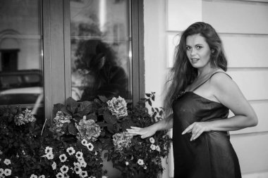 Siyah beyaz bir fotoğraf, yeşil elbiseli bir kız şelalenin yanında duruyor.