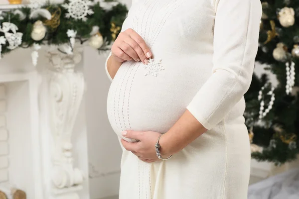 Kobieta w ciąży, obejmując jej brzuch, kominku — Zdjęcie stockowe