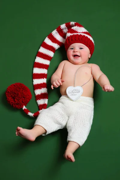 Bonito alegre natal bebê em um gnome vermelho e branco chapéu de cauda longa — Fotografia de Stock