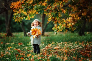 Laughing girl holding orange leaves clipart