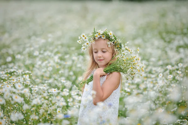 Meisje in bloem krans op het gebied van madeliefjes — Stockfoto