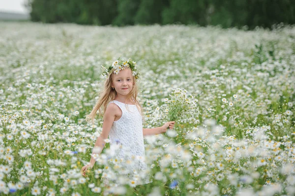Mädchen im Blumenkranz im Gänseblümchenfeld — Stockfoto