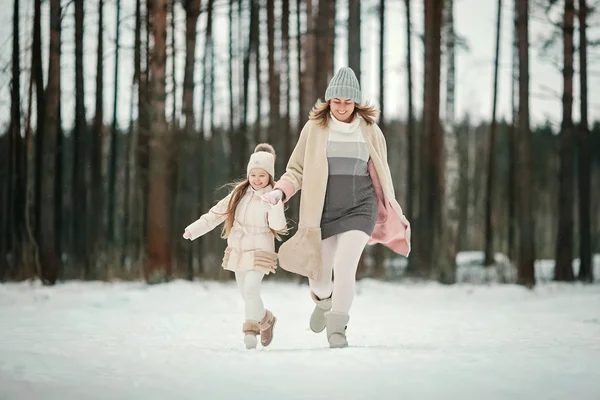 mother and daughter running in winter forest