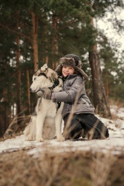 Kıvırcık saçlı küçük çocuk Sibirya köpeğine sarılıyor. 