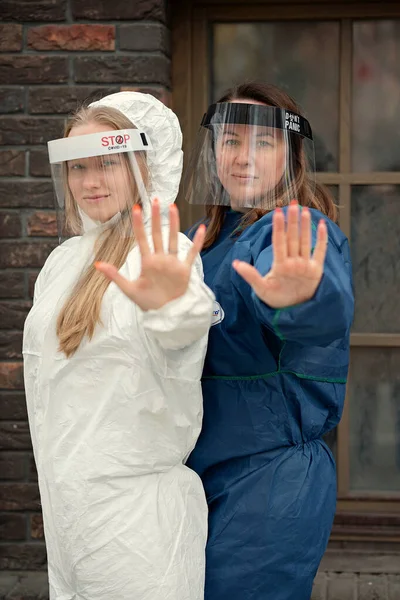 Two young women wearing protection medical screens or plastic shields on their face, for corona virus or Covid-19 protection.