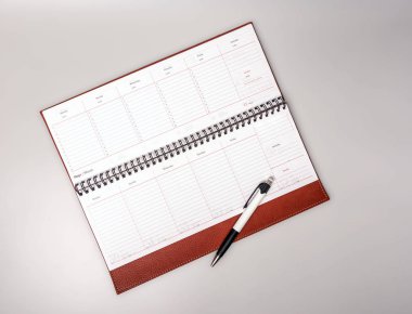 Gri arka planda bir kalemle deri ciltlenmiş açık bir defter. Metin için yer.