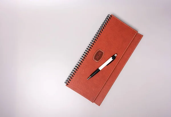 Closed notebook in leather binding with pen on a gray background. Place for text.