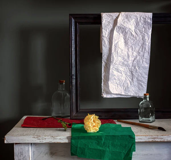 Still life with roses, bottles, picture frame and colored paper. Vintage. Retro.