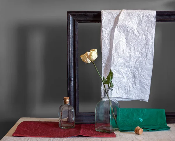 Still life with roses, bottles, picture frame and colored paper. Vintage. Retro.