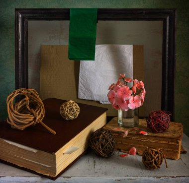 Masanın üzerinde kitaplar, ipler ve dallar var. Çiçek açan sardunya. Tablolar ve kağıtlar için ahşap çerçeve. İç mekan.