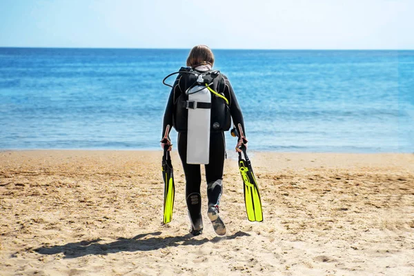 Mergulhador menina vai ao longo da praia em direção ao mar — Fotografia de Stock