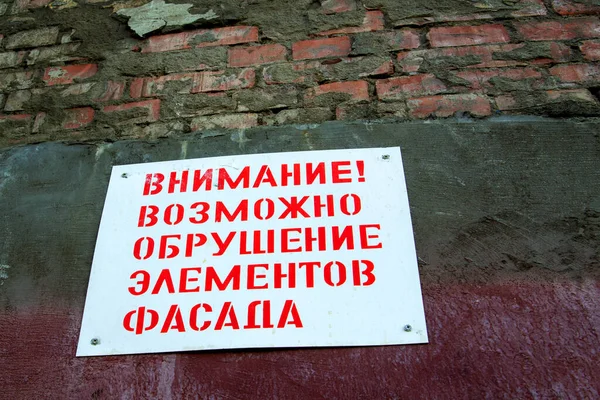 Тарілка на старому цегляному мурі, реставрація старого будинку. Російський текст старанно обвалив фасад. — стокове фото