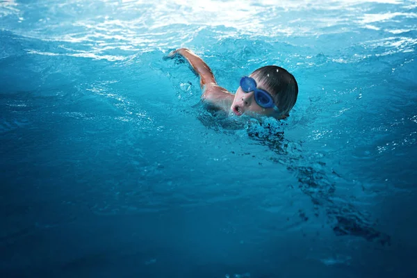 Mały sportowiec pływa w basenie przy raczku. Koncepcja szkolenia i sportu dla dzieci — Zdjęcie stockowe