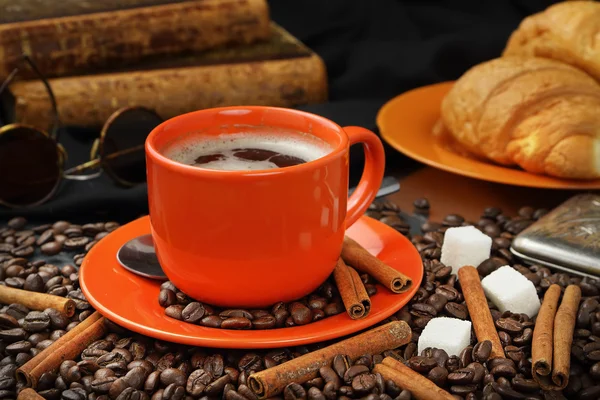 Natura morta caffè con una tazza arancione, cornetti e libri — Foto Stock