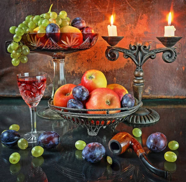 Still life with fruit in a vase, a glass of wine and candles