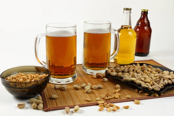 Bodegón con tazas de cerveza y pistachos en colores claros — Foto de Stock