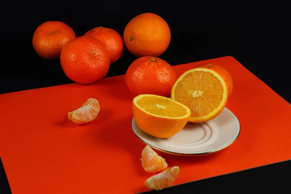 Tangerines and lemon on black and orange background