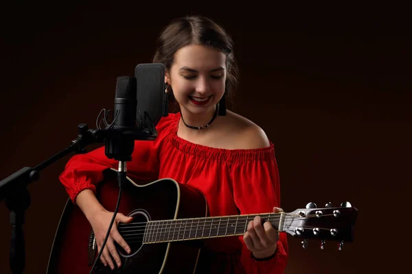 Chica con una guitarra delante de un micrófono de estudio — Foto de Stock