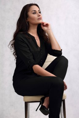 Siyah elbiseli güzel bir kadın, açık bir arkaplanda.