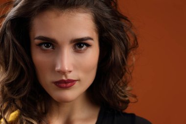 Açık kahverengi arka planda güzel bir kızın stüdyo portresi.